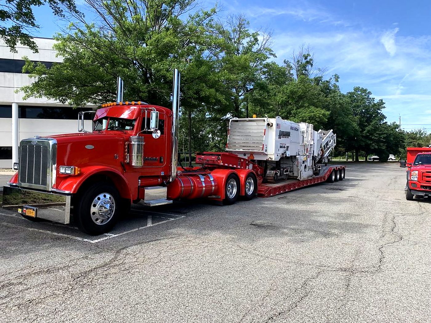 A milling machine loaded on a lowboy trailer behind the company truck